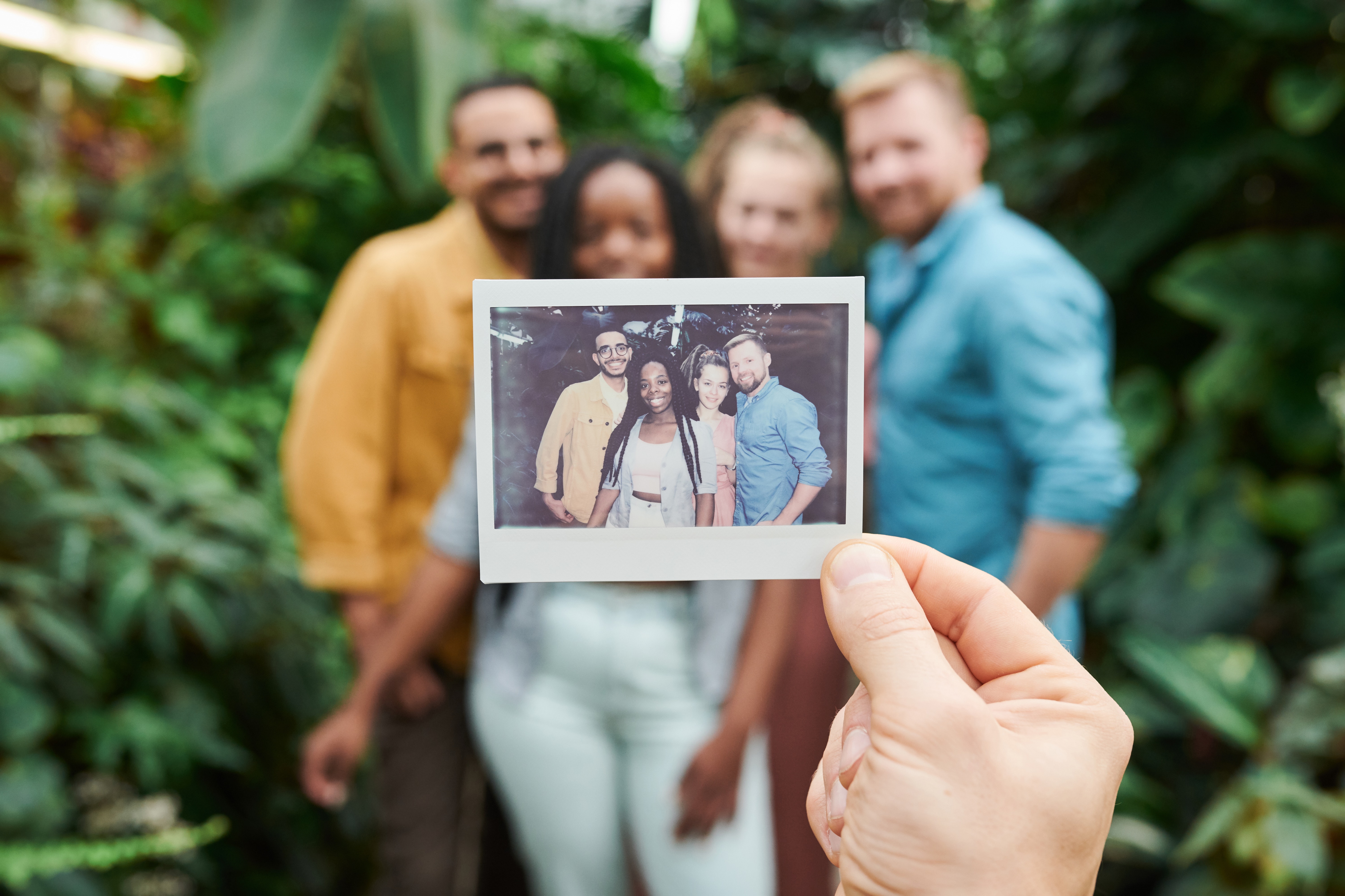 Groepsfoto polaroid met in de achtergrond de 4 mensen van op de foto