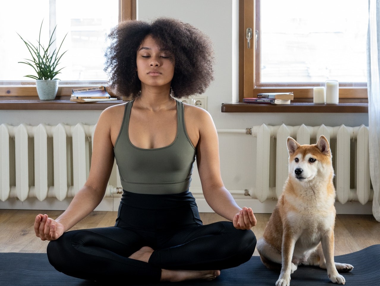 Vrouw mediteert op matje met hond naast zich