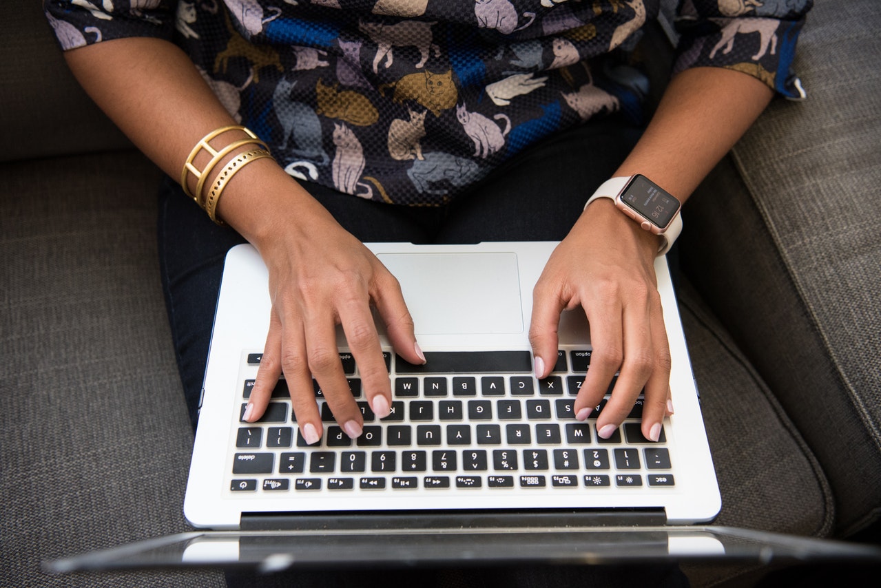 Persoon in bloemetjeshemd typt op laptop