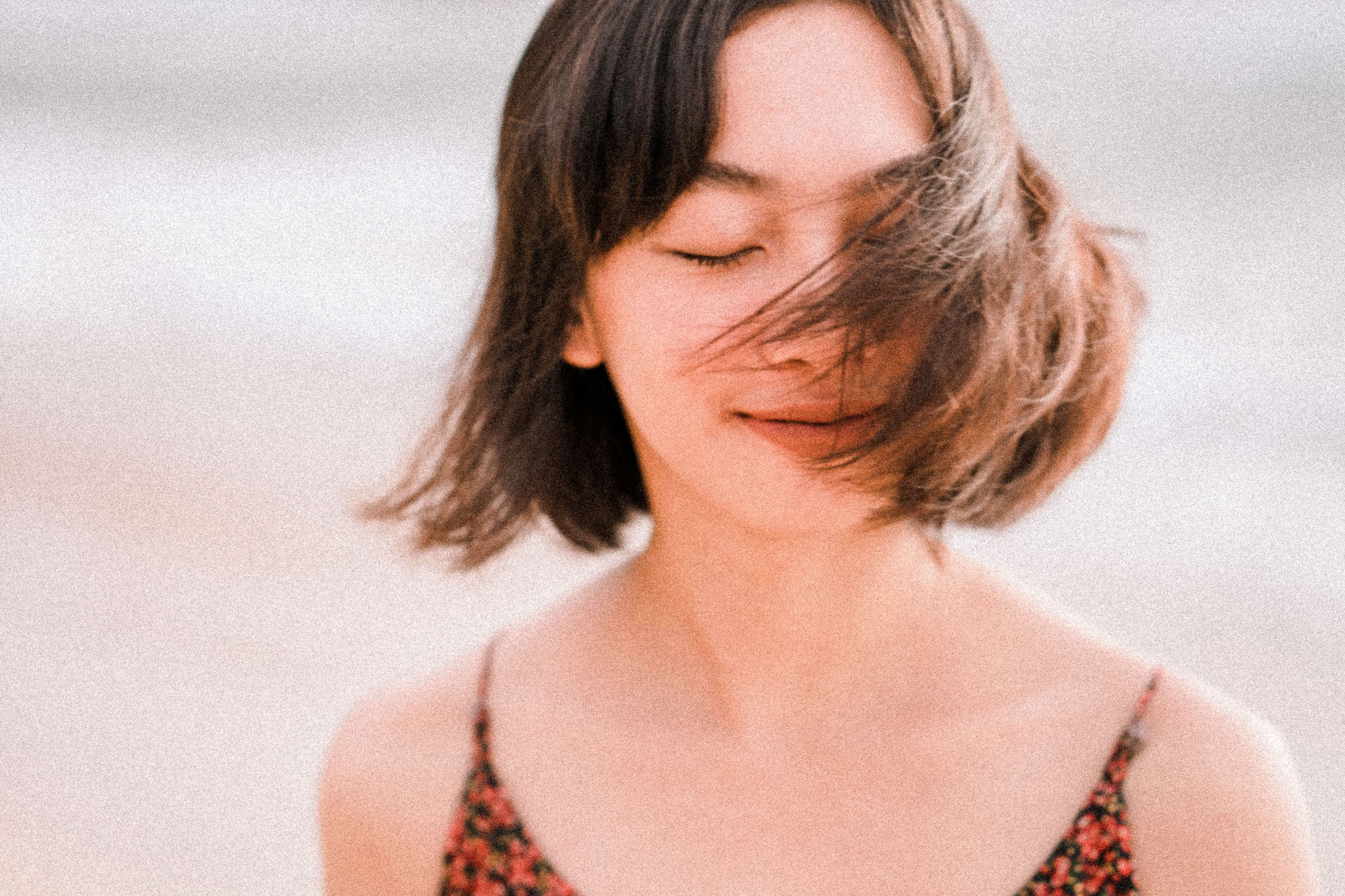 Vrouw aan zee met haar in de wind en ogen en gesloten