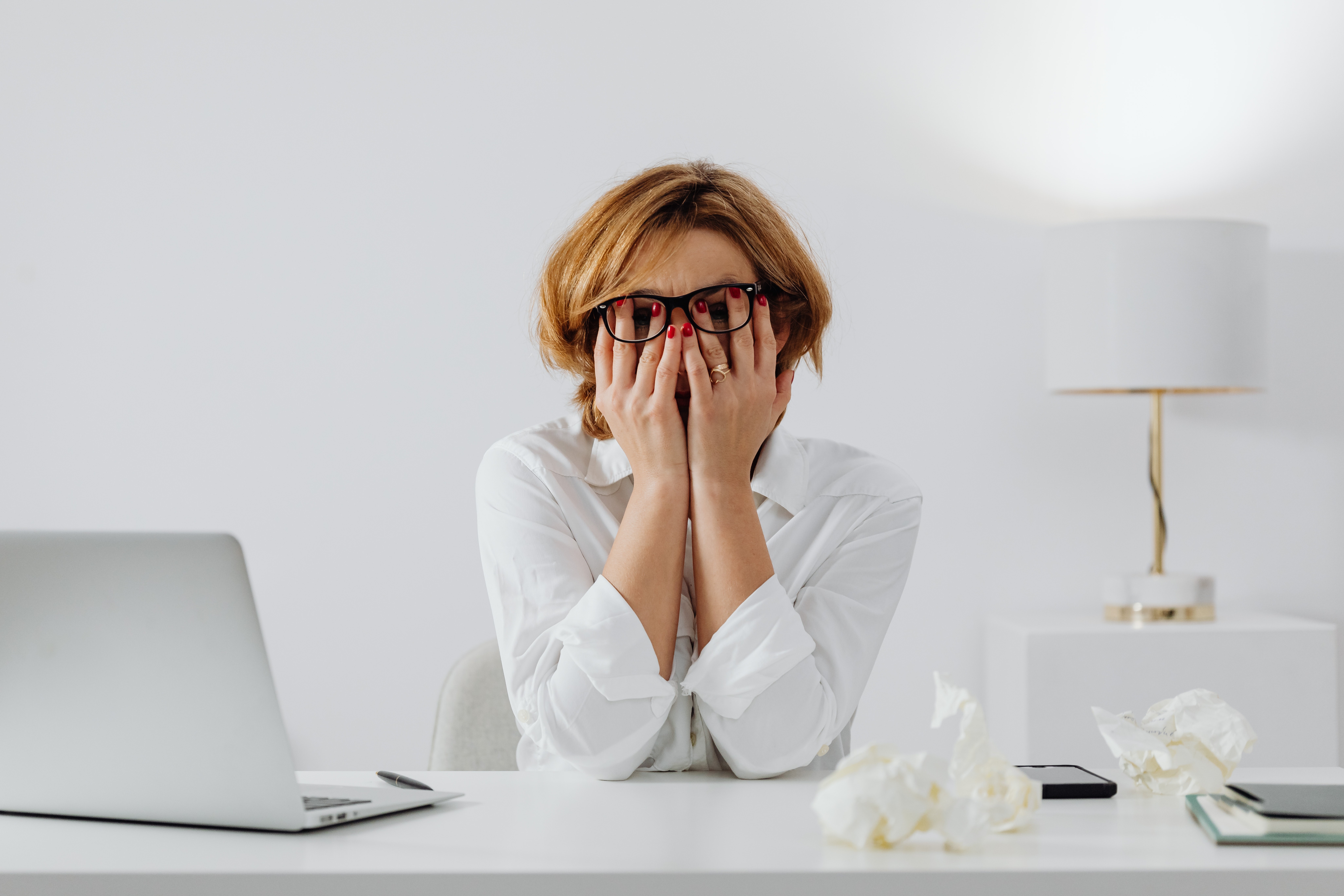 Vrouw aan bureau wrijft gefrustreerd over haar gezicht