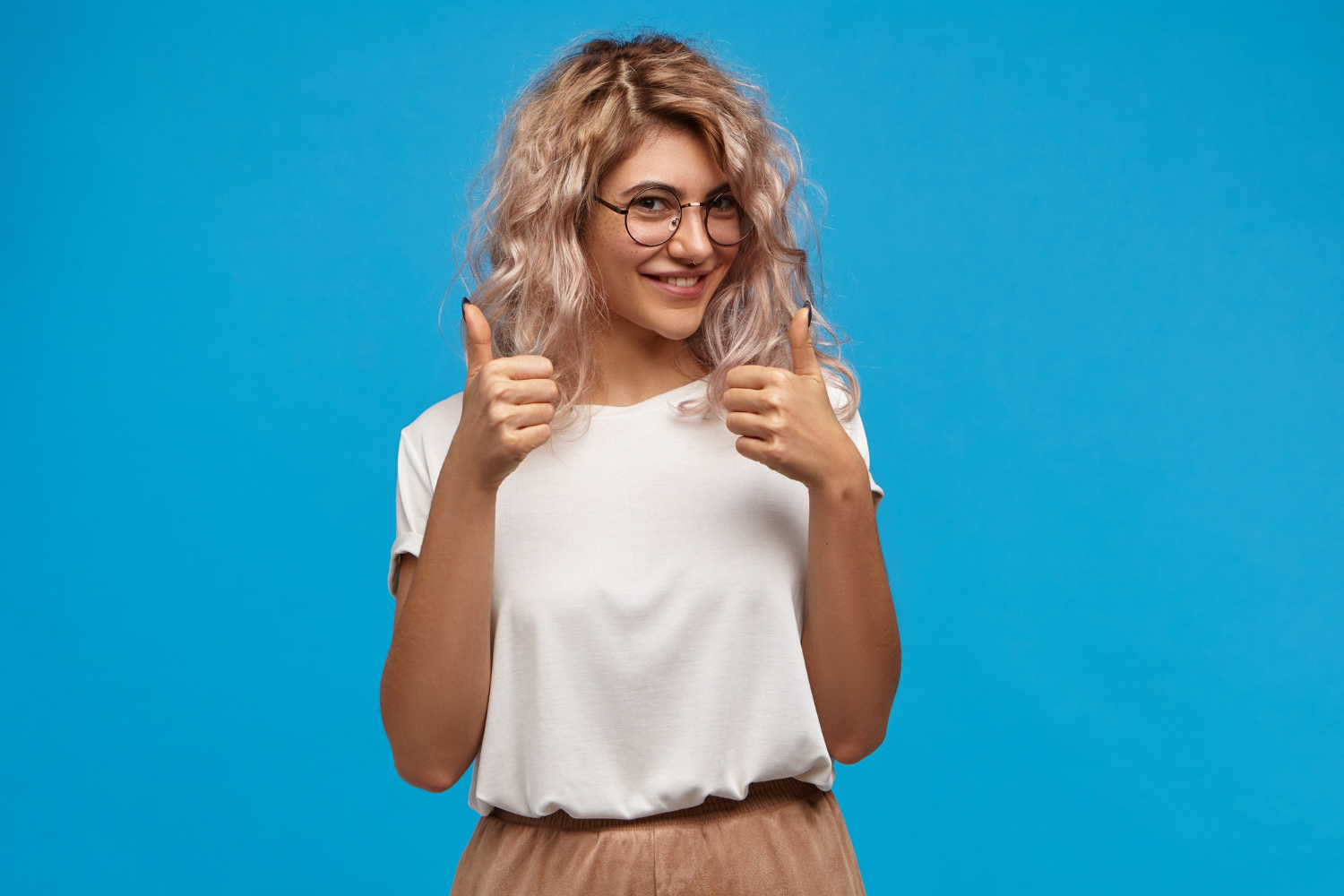 Vrouw met blonde krullen steekt haar twee duimen omhoog