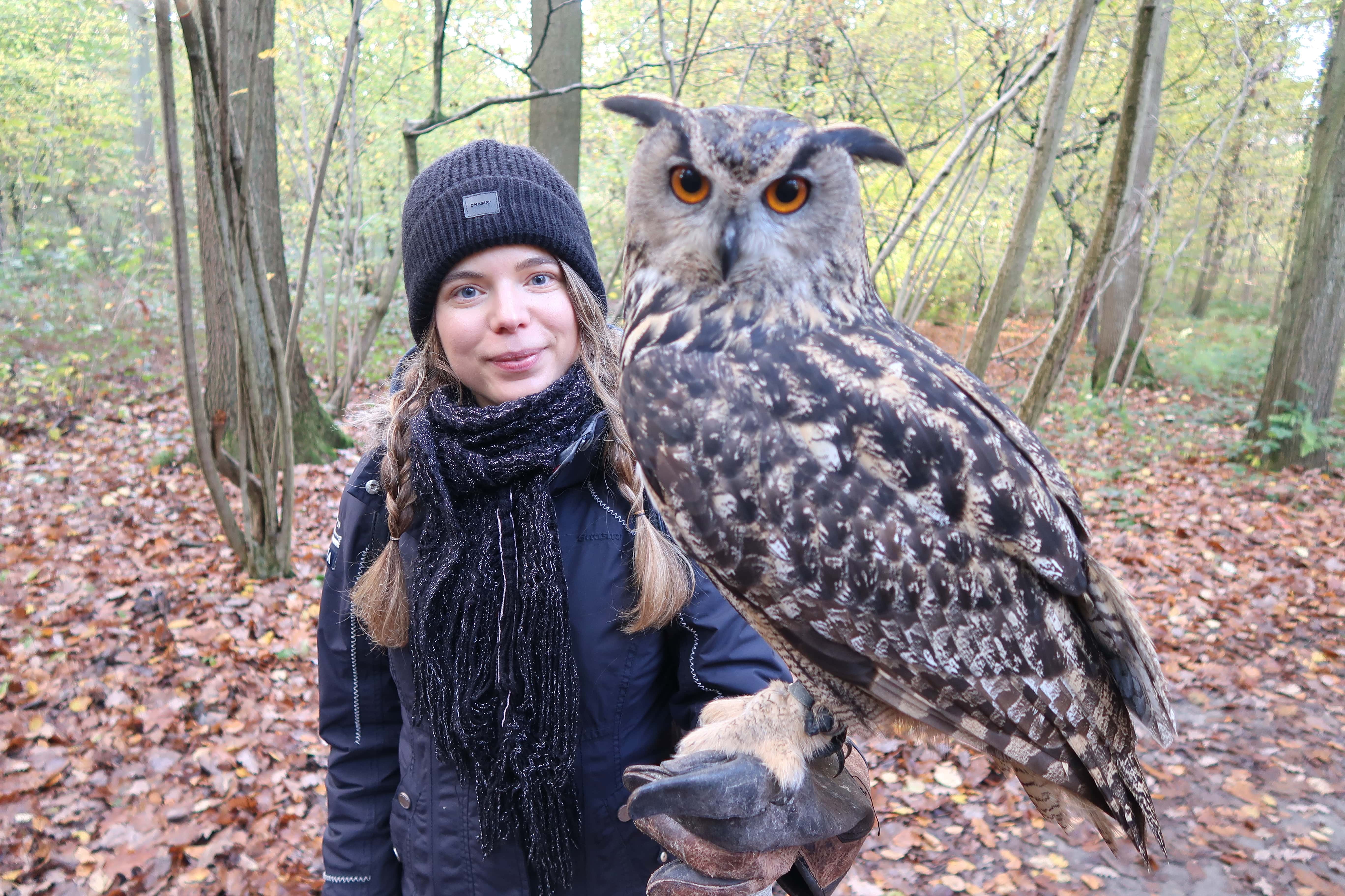 Charlotte in het bos, met muts en sjaal en grote oehoe op de arm