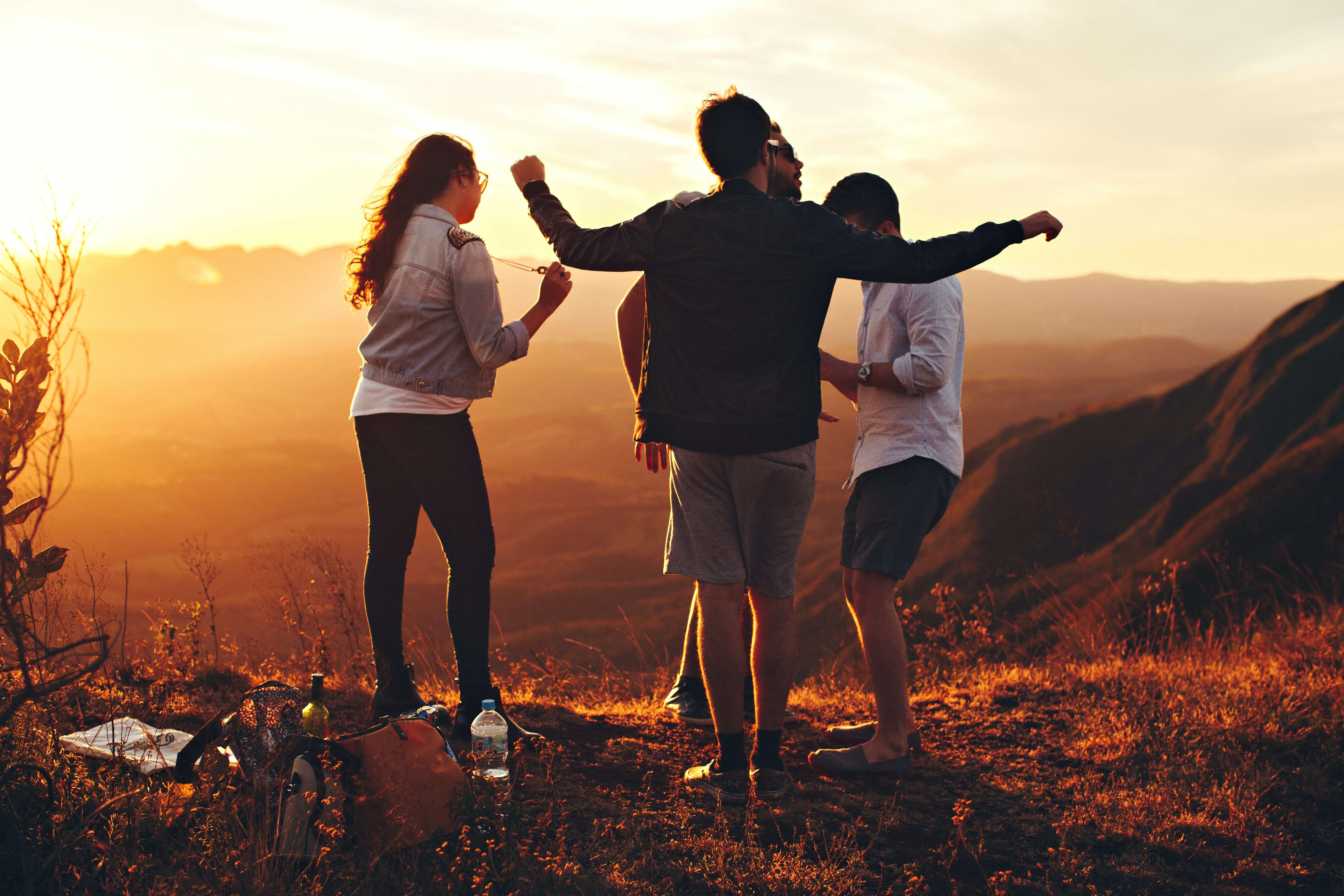 Vier tieners dansen op heuvel terwijl de zon ondergaat