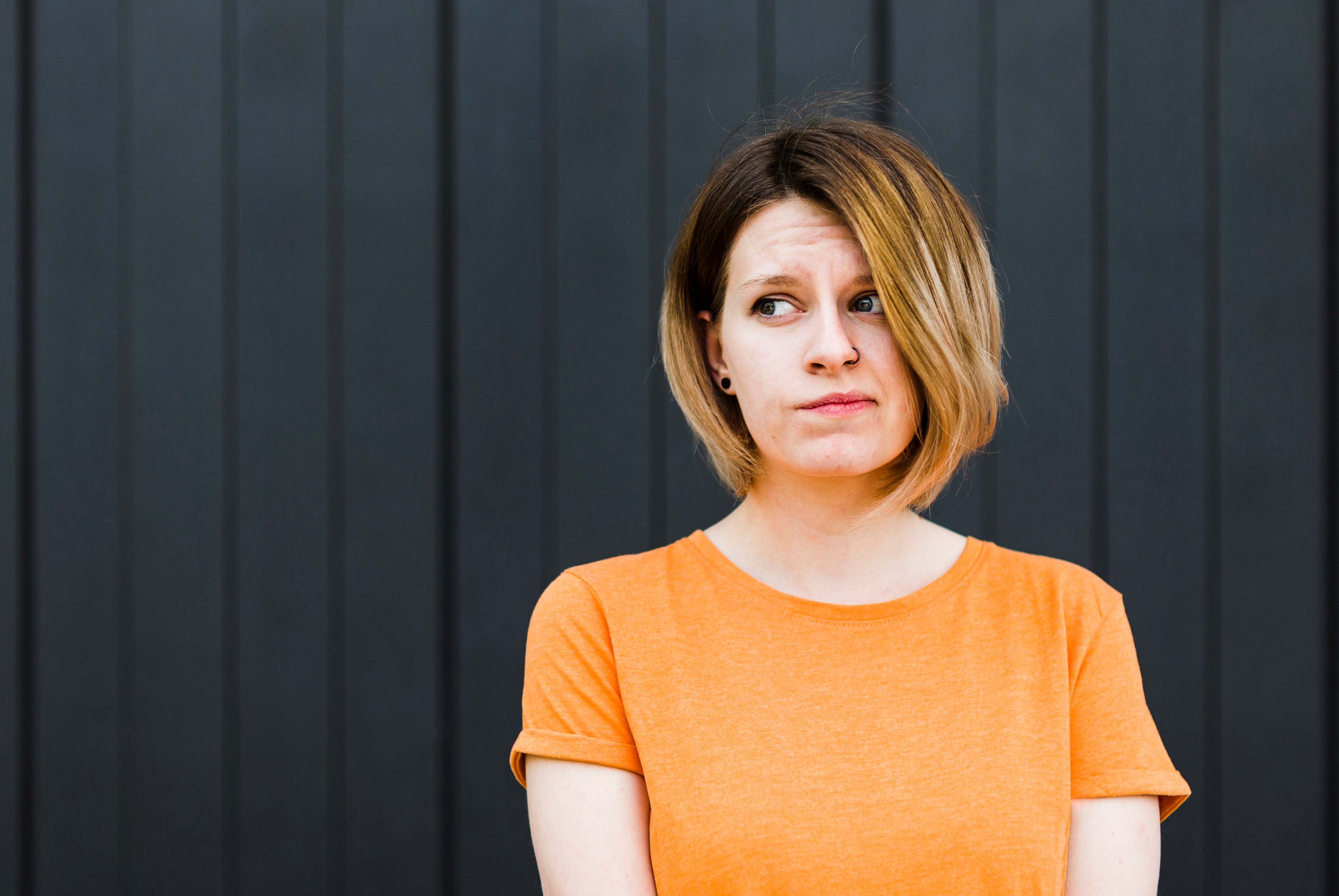 Vrouw in oranje t-shirt kijkt schuldbewust opzij