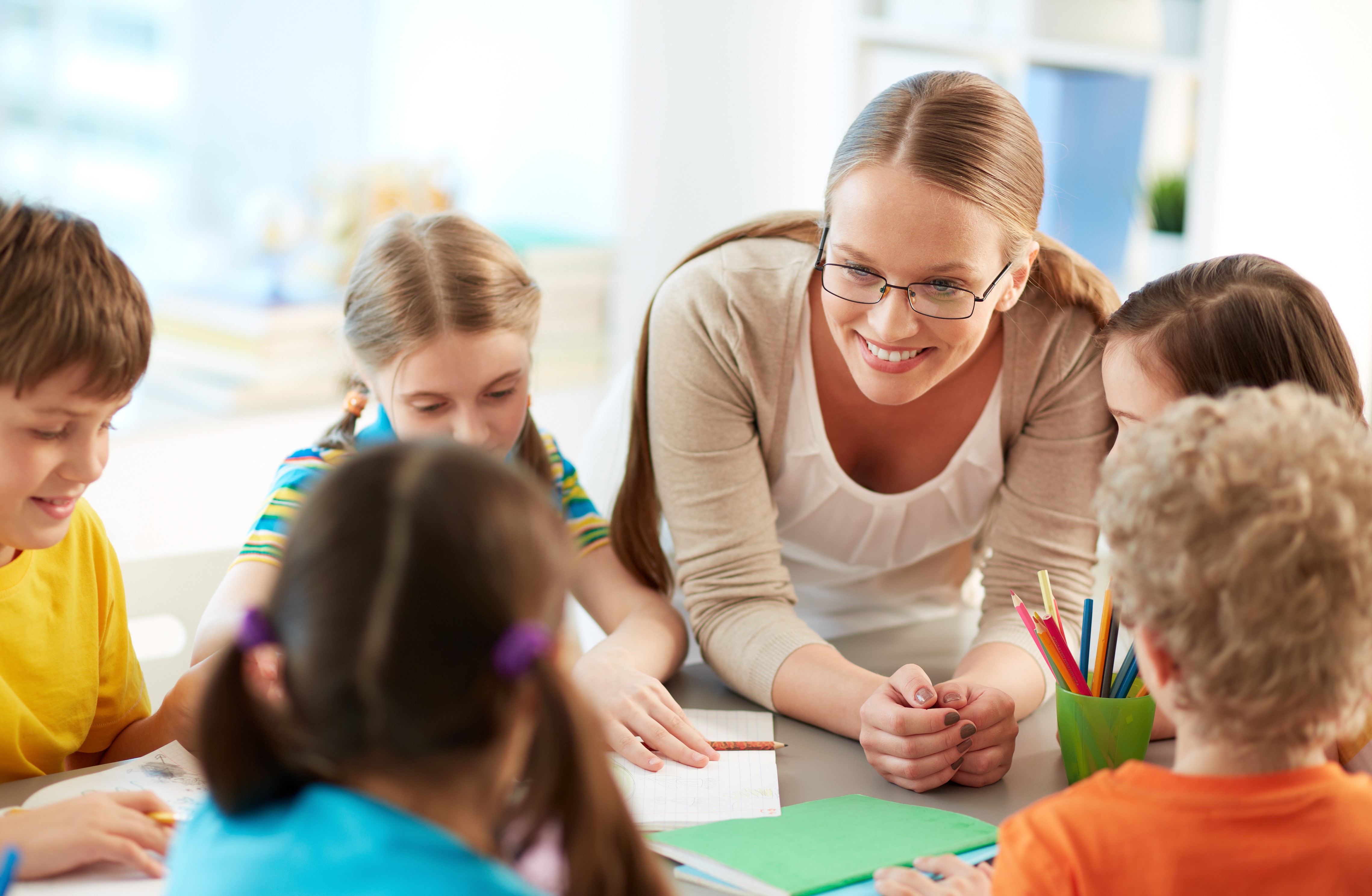 Leerkracht lagere school aan tafel met leerlingen