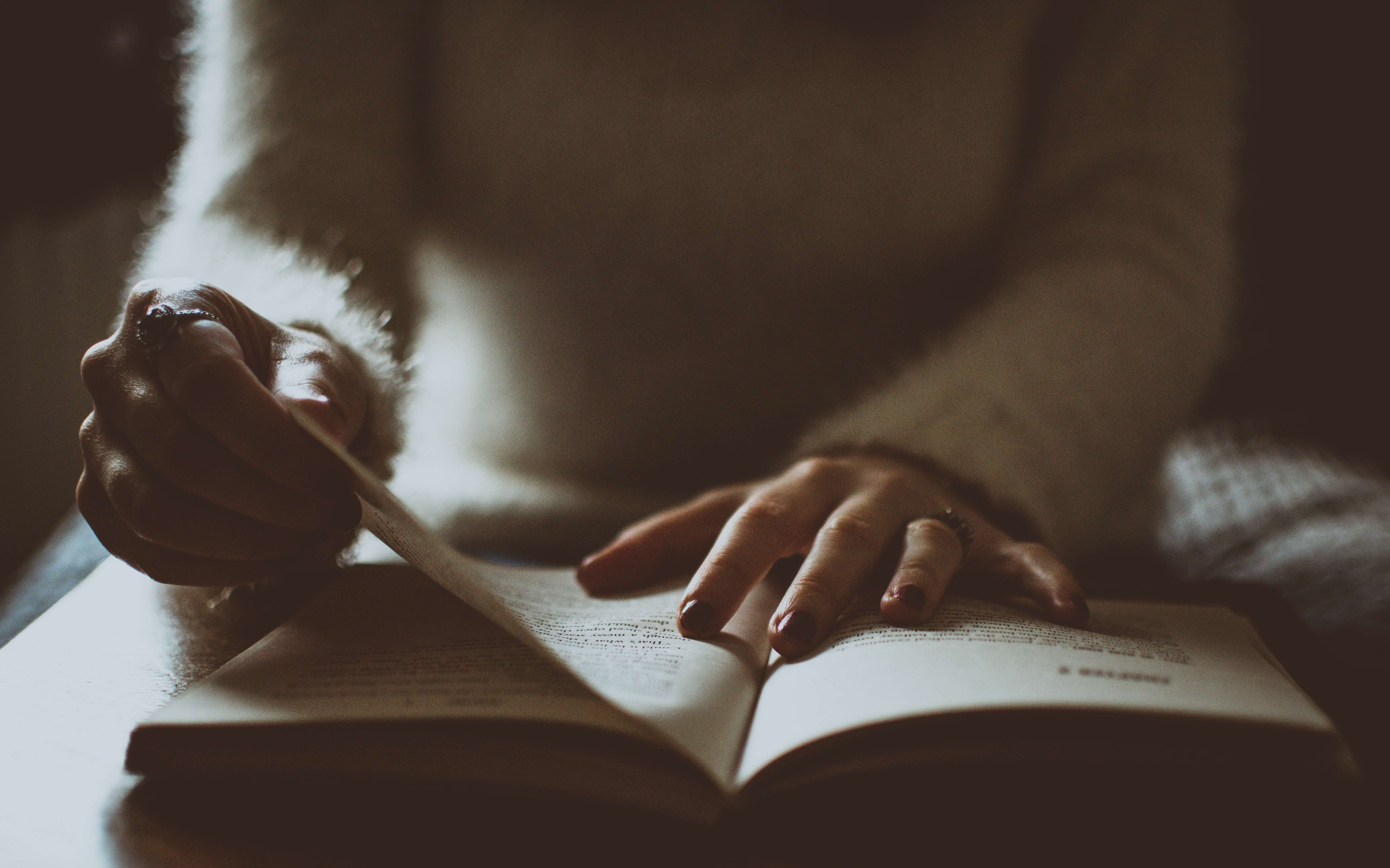 Handen van vrouw in pluizige witte trui, die een boek leest