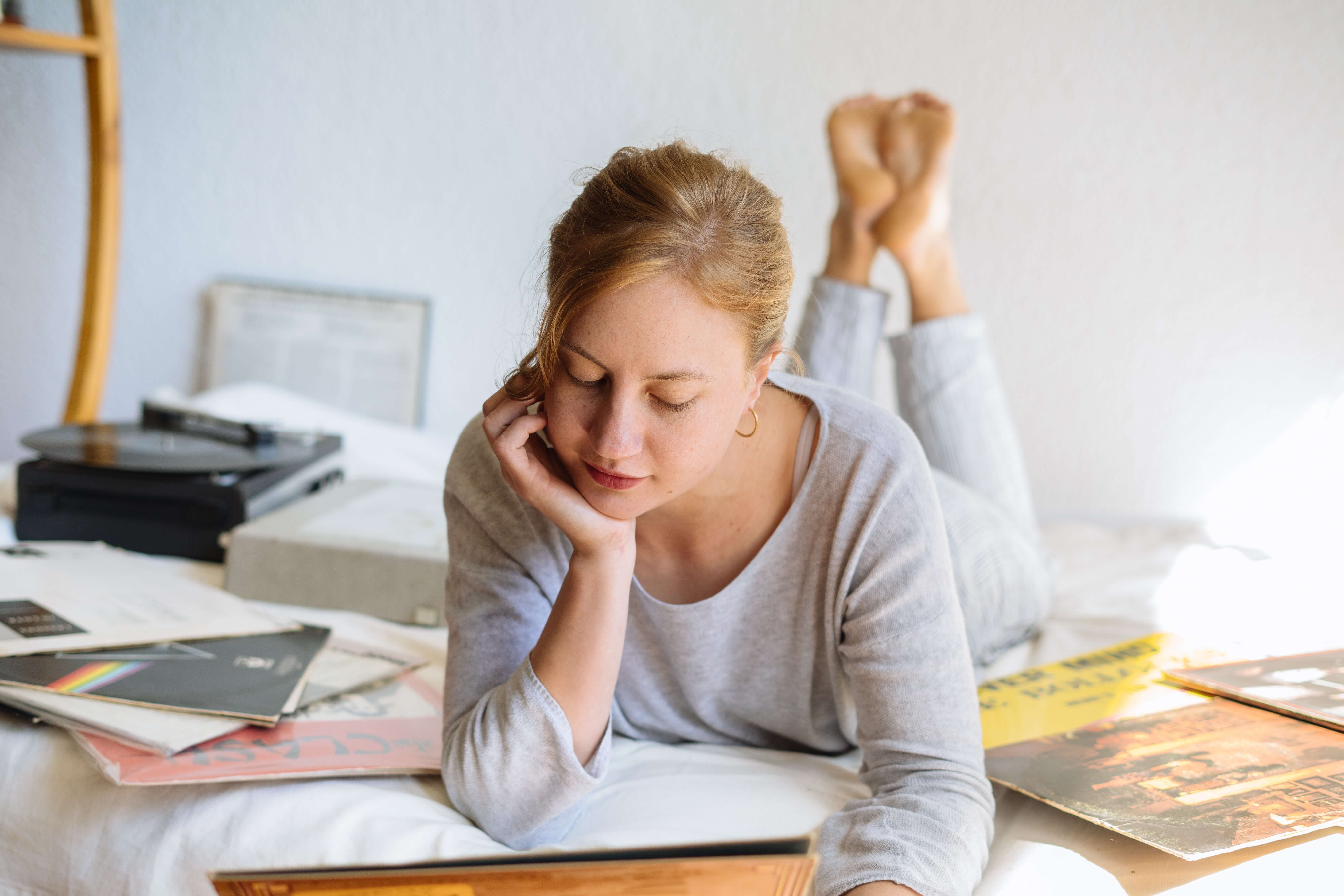 Vrouw in grijze pyjama leest magazines op bed