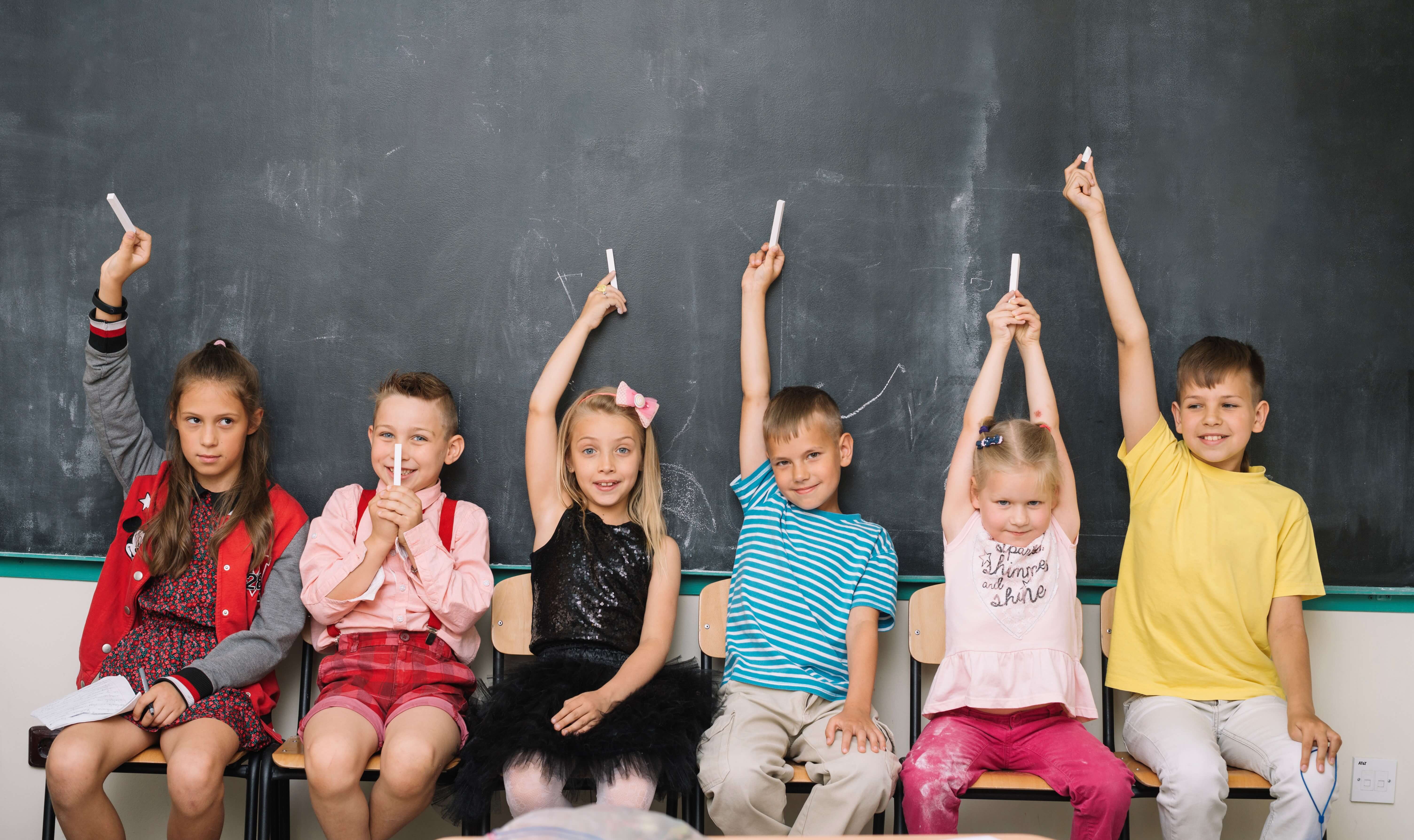 Kinderen voor krijtbord steken handen omhoog