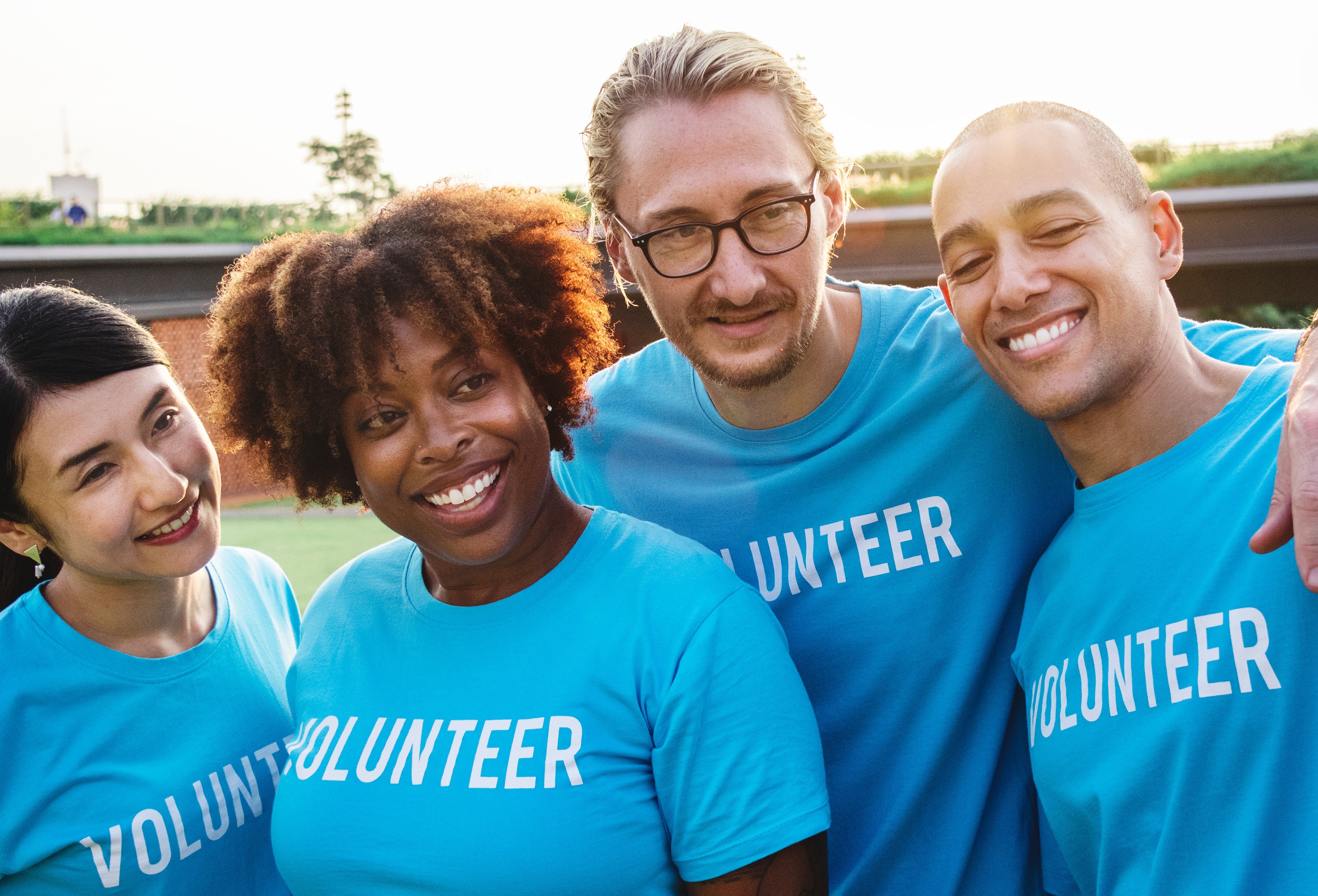 Vier mensen in blauwe t-shirt met tekst volunteer