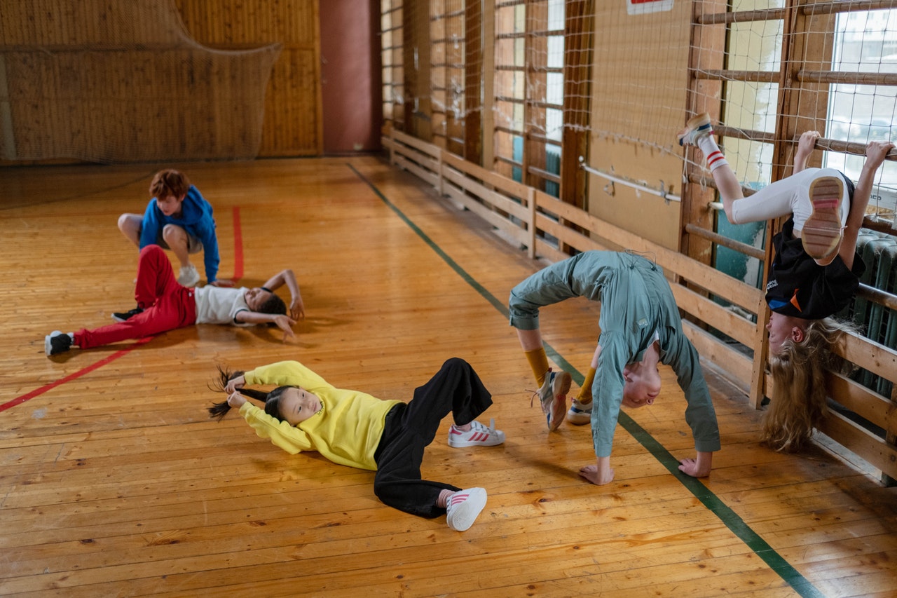 Kinderen in turnzaal doen gekke dingen op de grond en aan sportraam