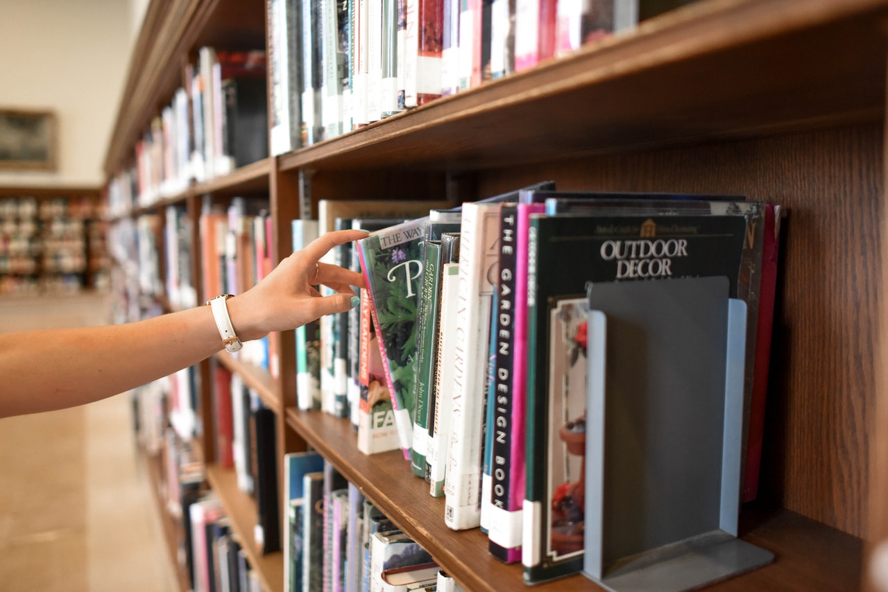 Persoon neem boek uit bibliotheek kast