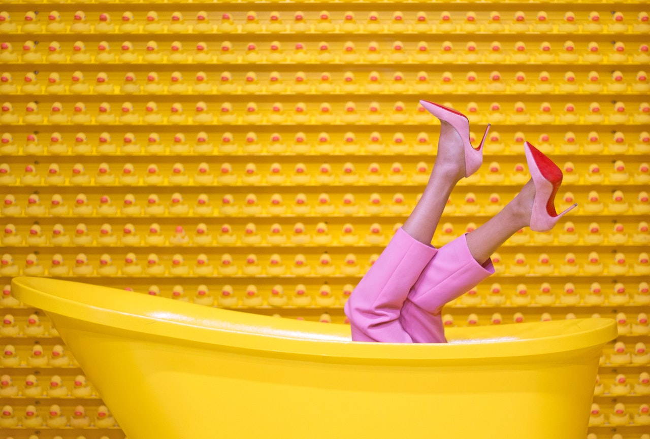 Gele badkuip waar benen in roze broek uit steken